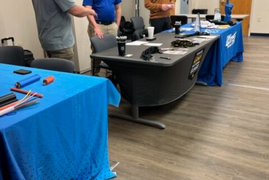 3 people standing at tables speaking to each other 