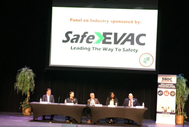 Panel sitting at tables on stage